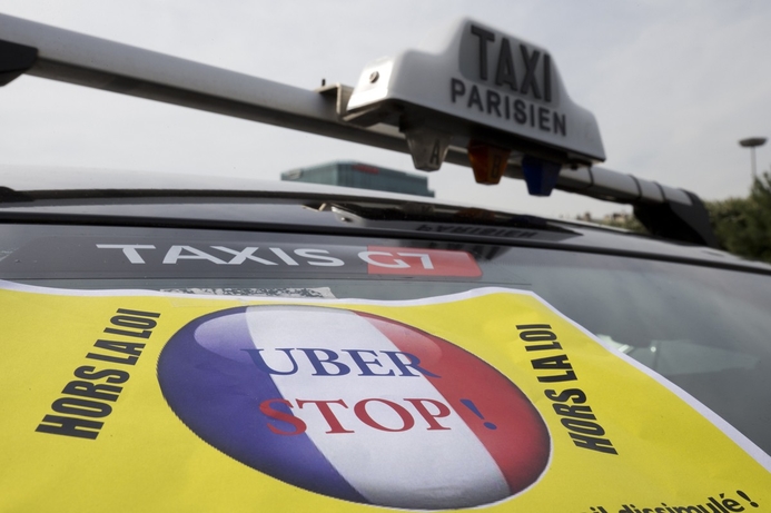A protest sign on a taxi in Paris reads ‘Hors la loi’ (outlaw). French taxi drivers see Uber as unfair competition. Uber puts hold on French operations in wake of protests, violence